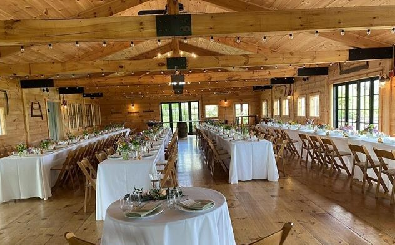 View of wedding seating inside a blonde-wood post-and-beam event hall.